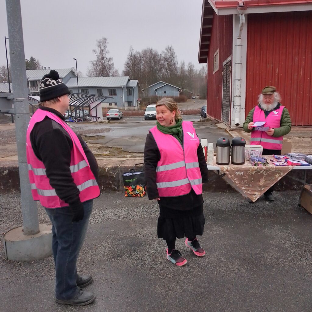 Oriveden asemalaiturilla pöytä, jolla on tarjoilua ja vaaliesitteitä. Kuvassa seisovat Juha Koistinen, Jaana Jämsén ja Reijo Kahelin.