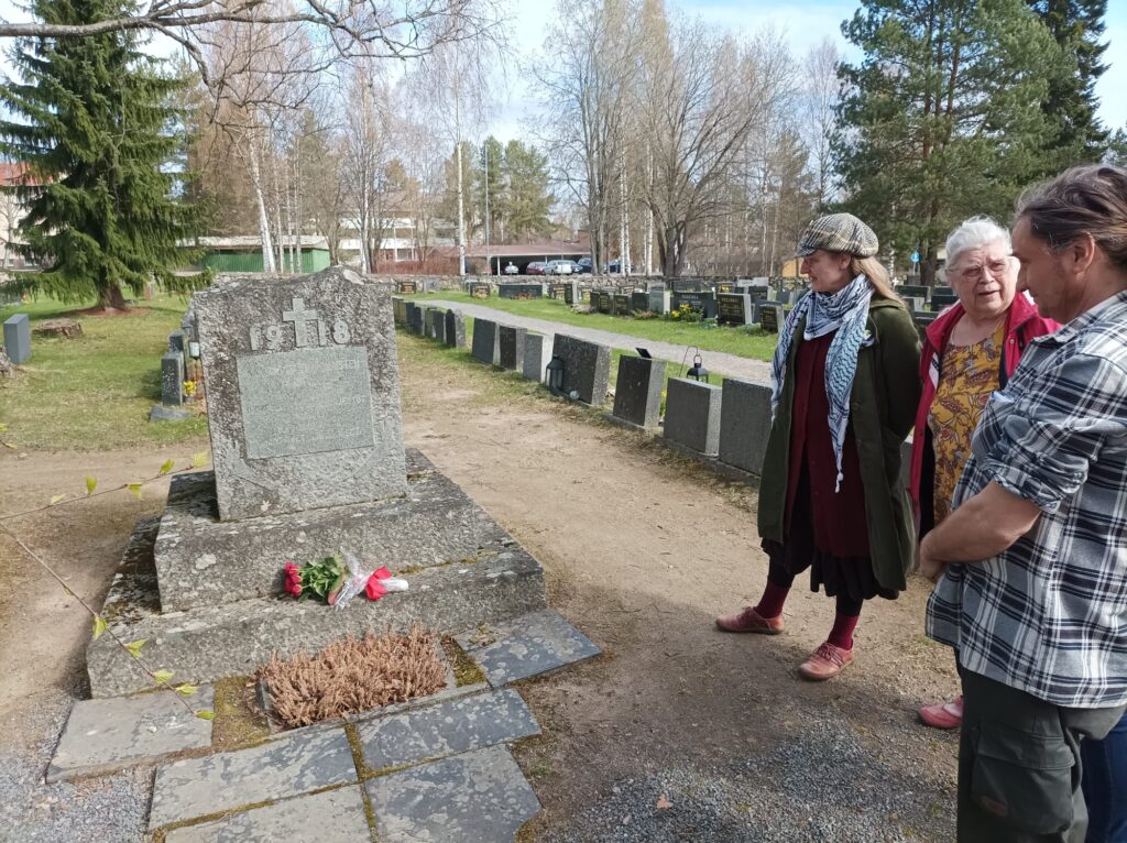 Punaisten muistomerkille on laskettu kukkia. Vieressä ihmisiä katselee muistomerkkiä kunnioittavasti.